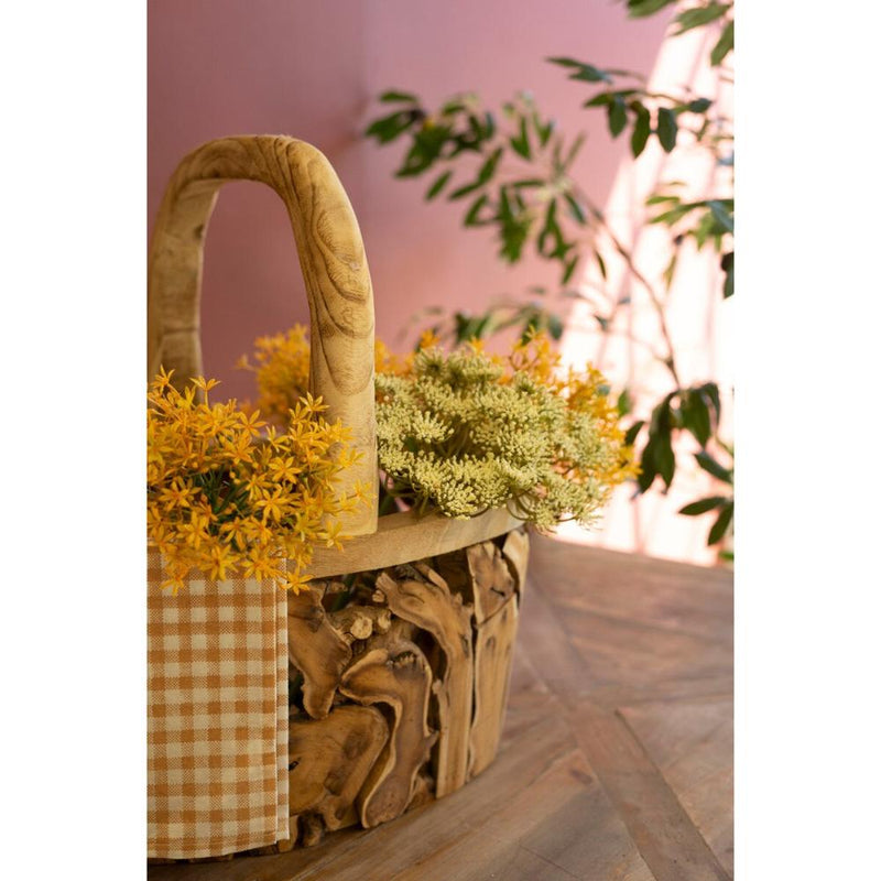 Kalalou Driftwood Baskets with faux florals, gingham cloth on a mixed wood table, softly framed by plants in the background.