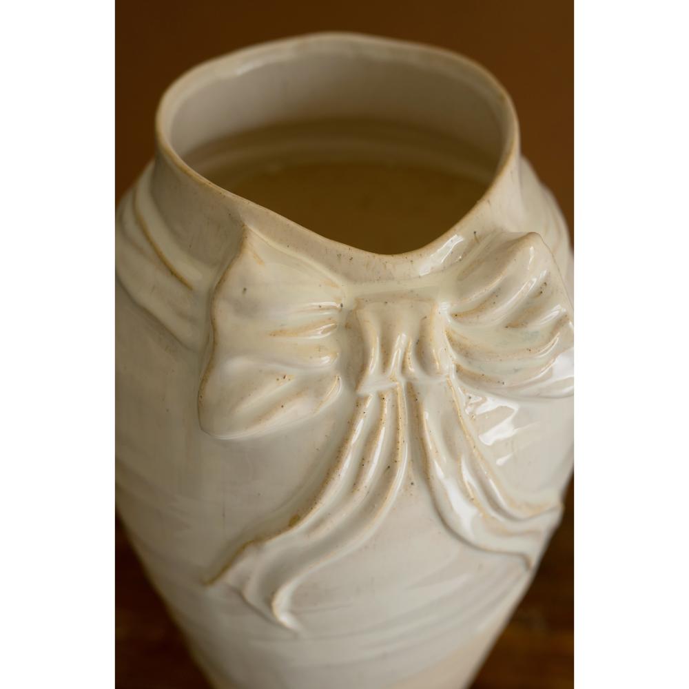White ceramic vase with a bow design on a brown background