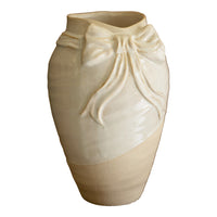 Beige ceramic vase with a decorative bow design on a white background