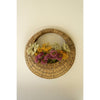 A Kalalou Woven Vine Wall Basket (set of 2) displays vibrant purple, yellow, and green flowers as natural decor.