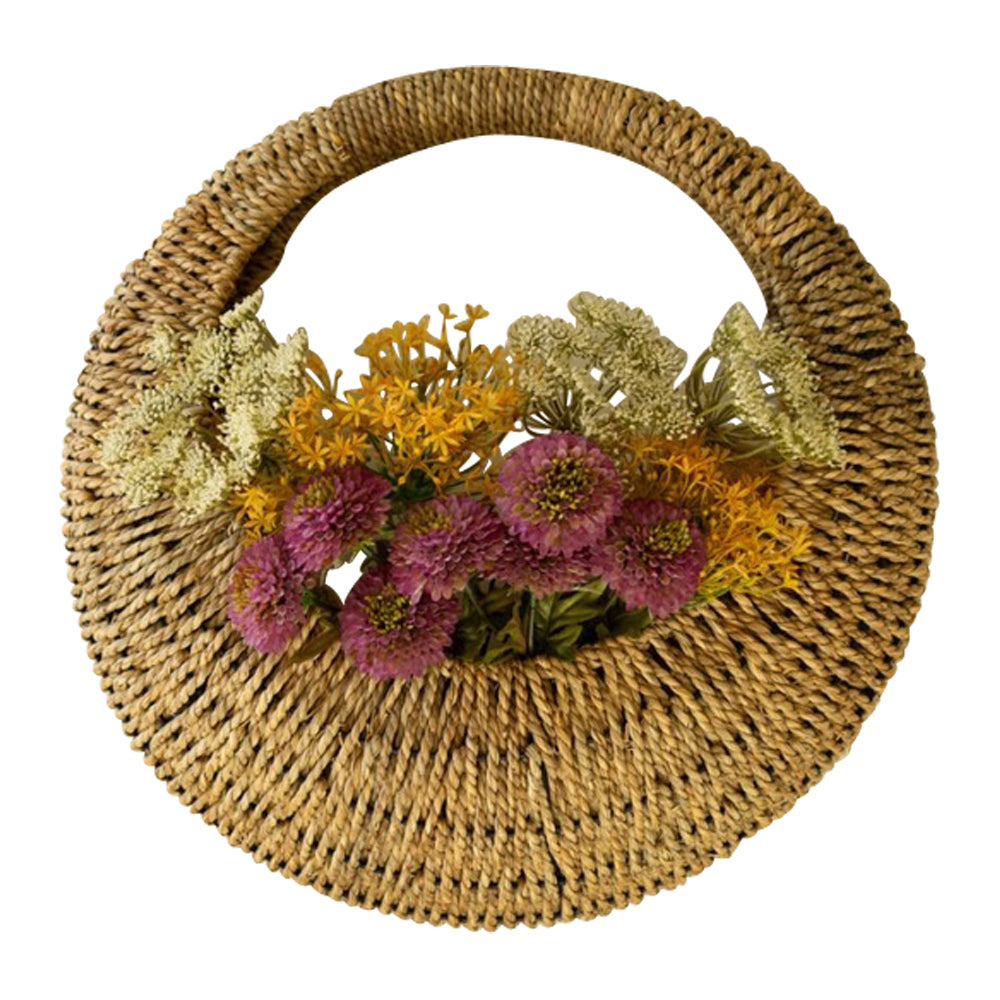 A Kalalou Woven Vine Wall Basket (set of 2) displays vibrant purple, yellow, and green flowers as natural decor.