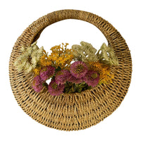 A Kalalou Woven Vine Wall Basket (set of 2) displays vibrant purple, yellow, and green flowers as natural decor.