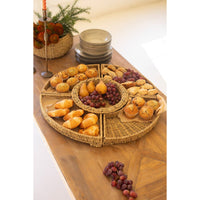 Wicker platter with assorted pastries and fruits on a wooden table.