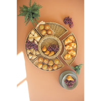 Woven tray with assorted pastries and grapes on a peach-colored surface