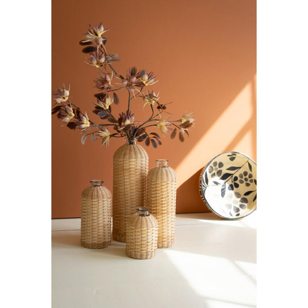 Set of woven vases with a plant against an orange wall