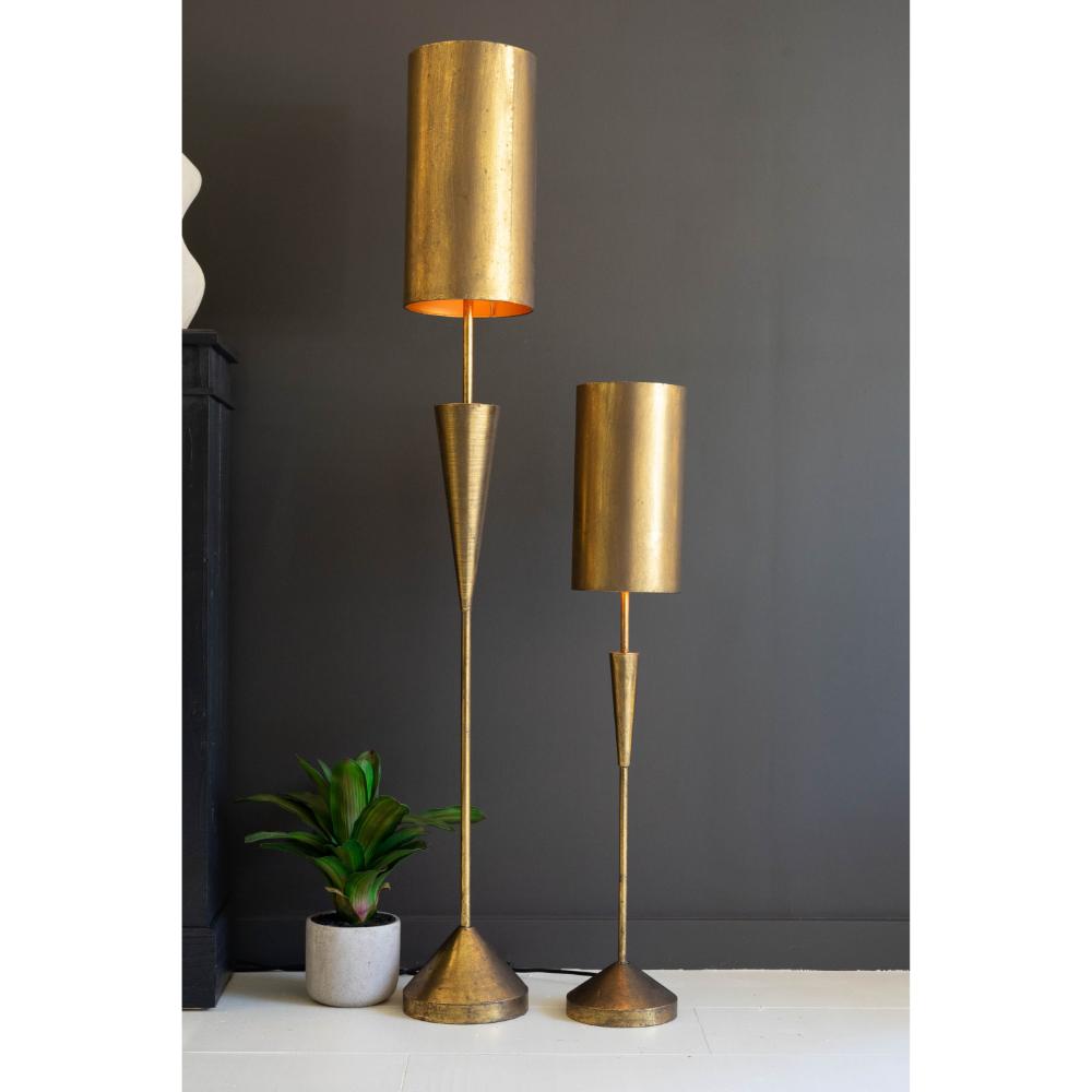 Two gold floor lamps on a white surface with a dark gray wall background