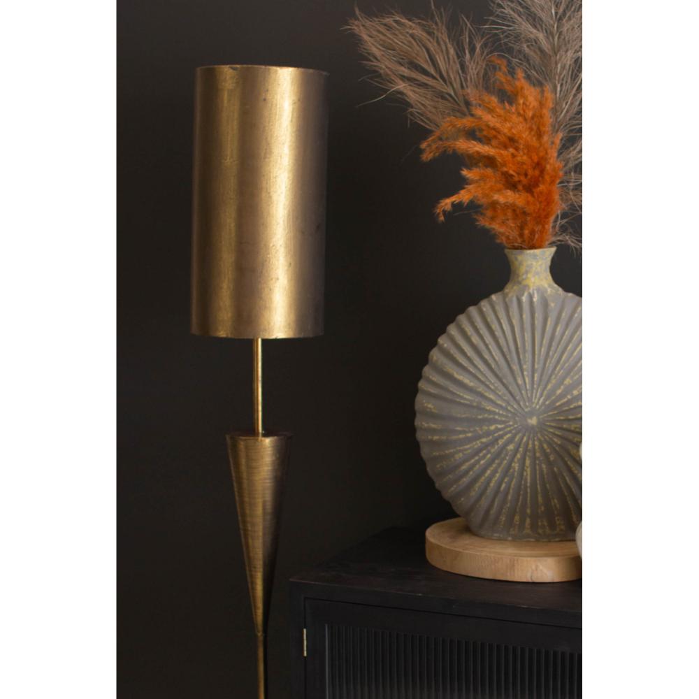 Gold floor lamp against a dark wall with decorative elements.