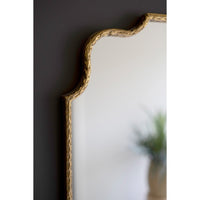 Gold-framed mirror on a dark wall with a blurred background