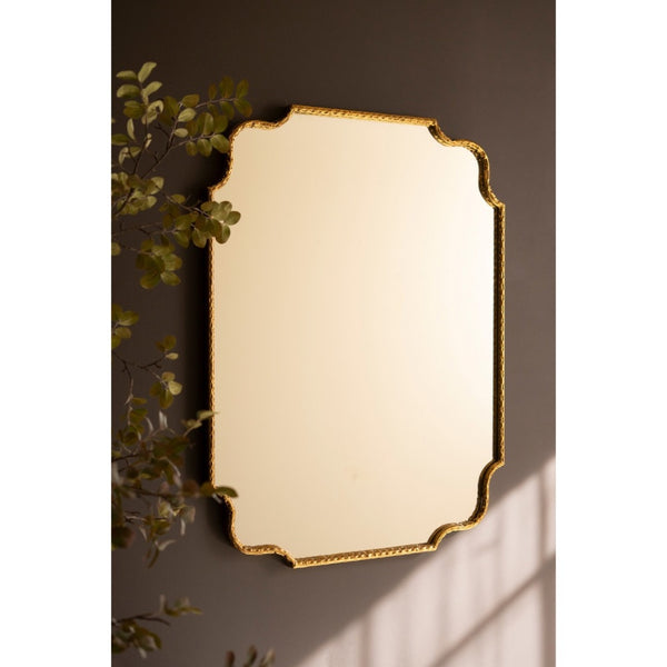 Decorative wall mirror with gold frame on a dark wall