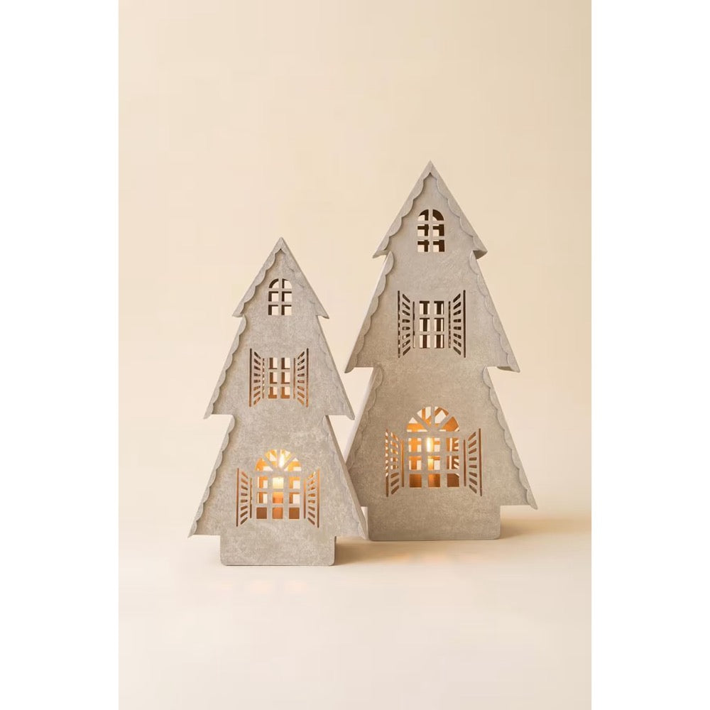 Two small tree-shaped decorative lights with cutout windows and shutters, glowing with warm light from within, set against a plain beige background.