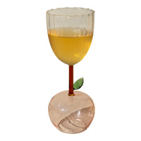 An Apple Base Wine Glass from Kalalou, with orange liquid and a leaf