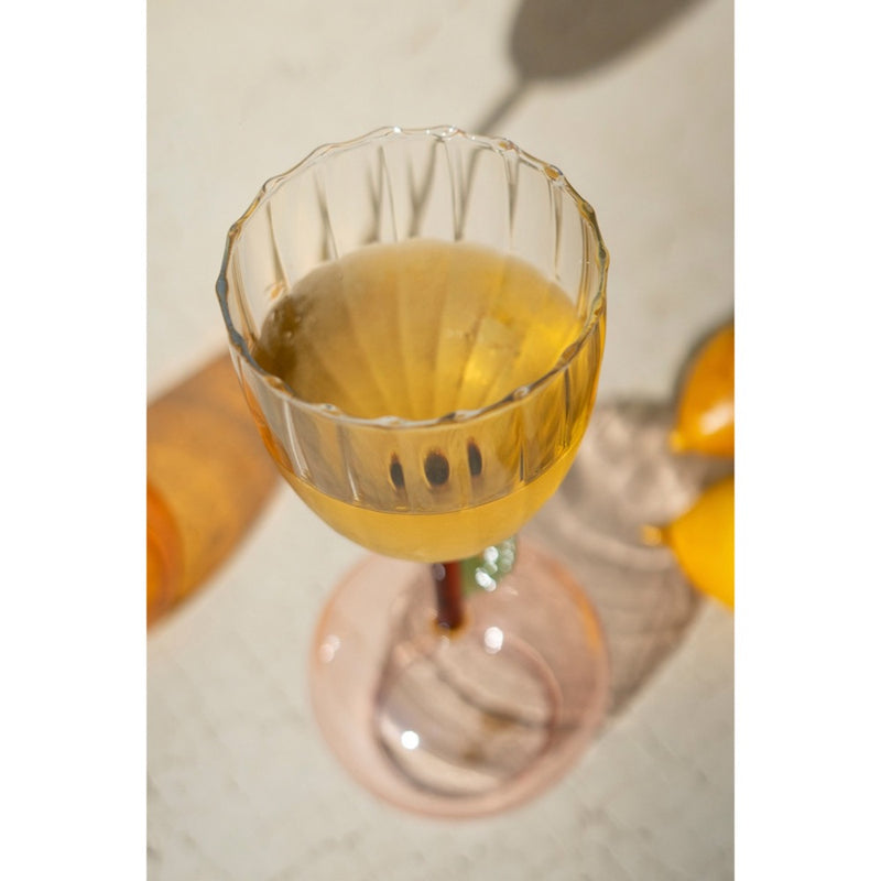 A Kalalou Apple Base Wine Glass from a set of 6 on a table with lemons, casting shadows from the home bar.