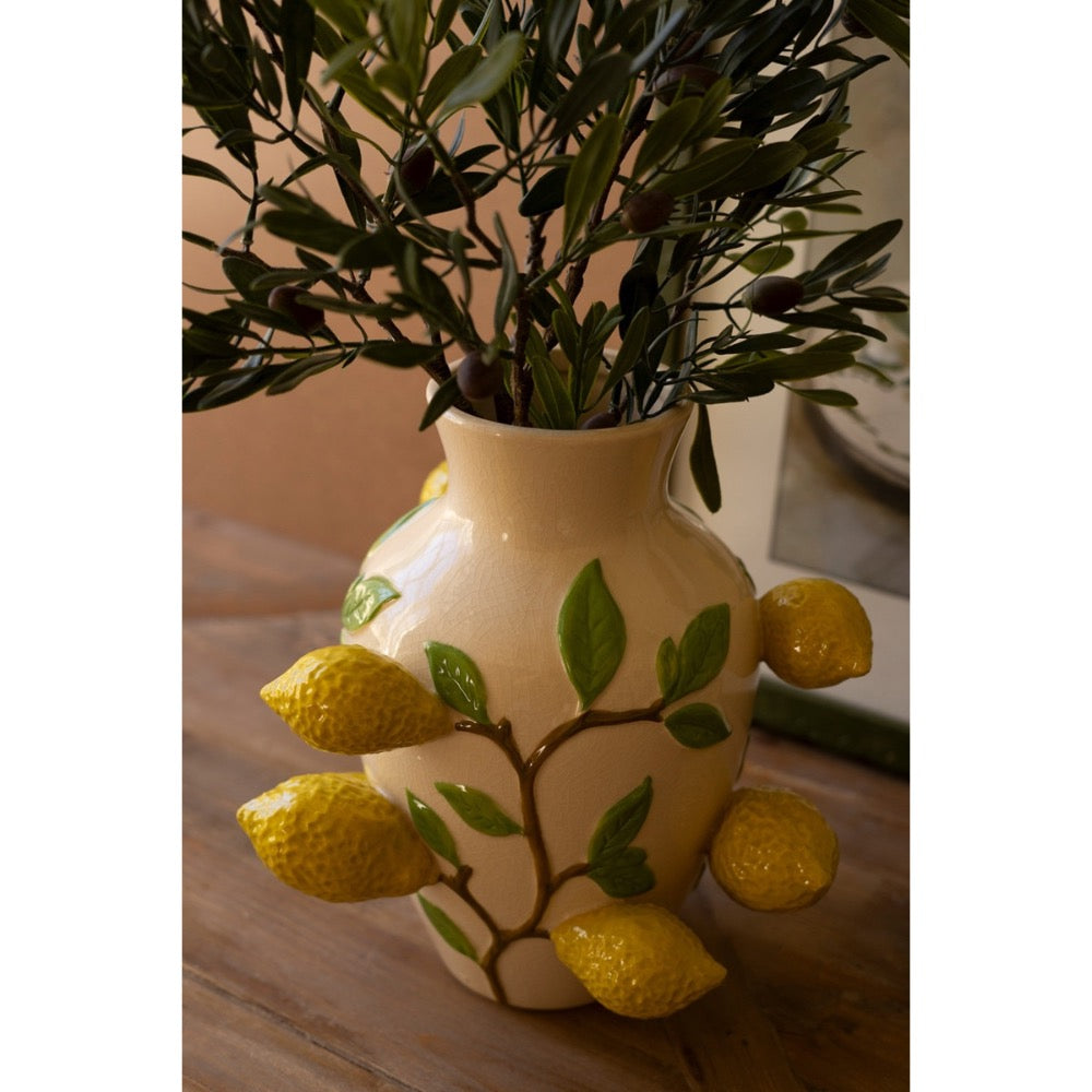 The Kalalou Ceramic Lemons Vase holds branches on a wooden table with its versatile design of lemons and leaves.