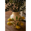The Kalalou Ceramic Lemons Vase holds branches on a wooden table with its versatile design of lemons and leaves.