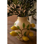 The Kalalou Ceramic Lemons Vase holds branches on a wooden table with its versatile design of lemons and leaves.