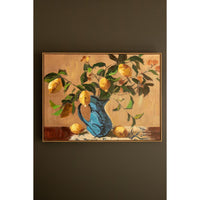 A framed still life painting of lemons in a blue pitcher, displayed on a dark brown wall.
