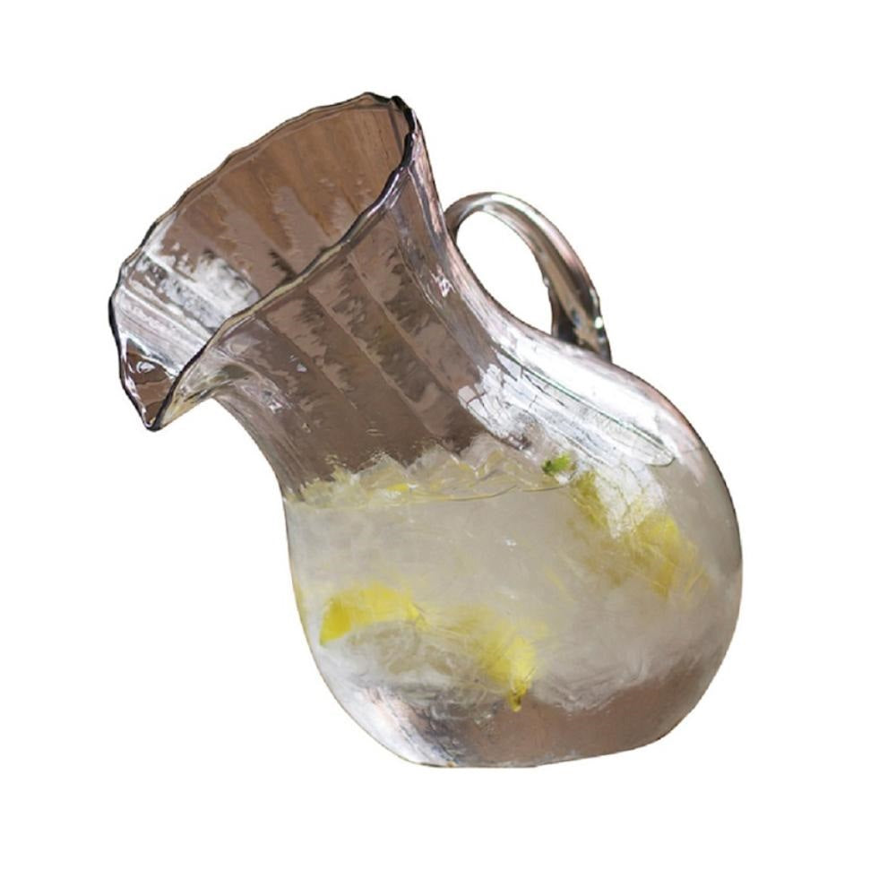 Clear glass pitcher filled with a lemonade mixture on a white background