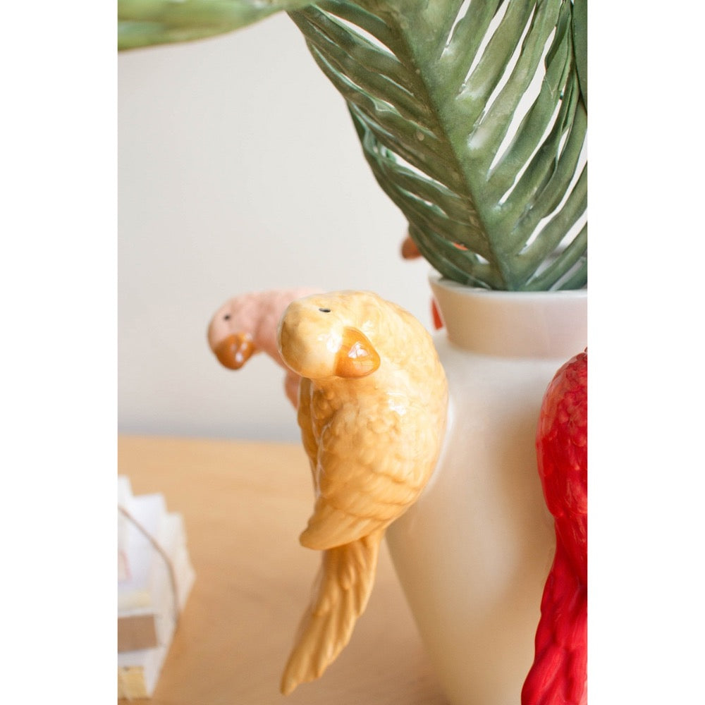 Decorative bird  figurine on a vase with green leaves in the background