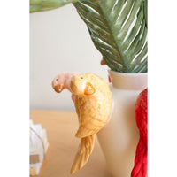 Decorative bird  figurine on a vase with green leaves in the background