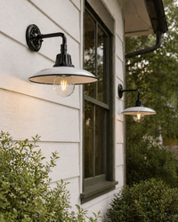 Outdoor wall lights on a house exterior with greenery around.