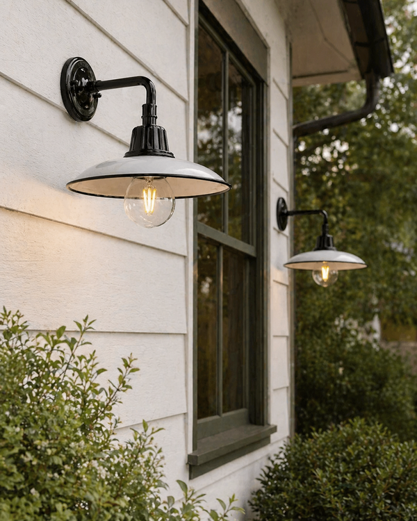 Outdoor wall lights on a house exterior with greenery around.