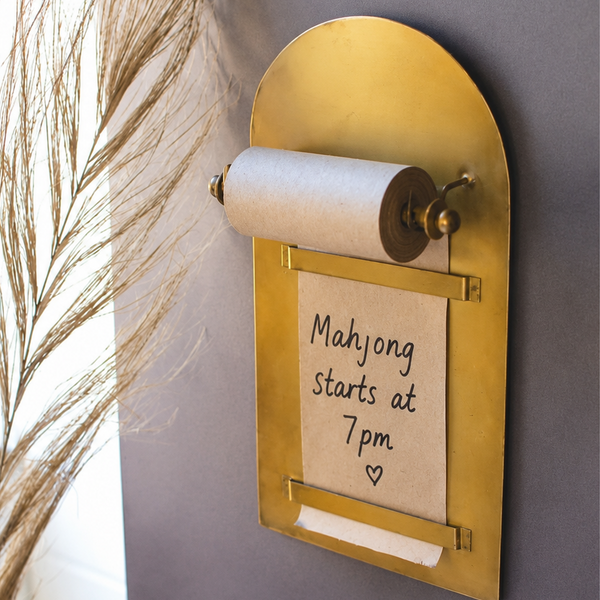 Kalalou Wall Mounted Antique Brass Magnetic Note Roll, shown with "Mahjong starts at 7pm ♥" handwritten on the sheet.