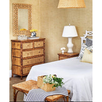 Cozy bedroom featuring Kenian Tortoise Shell Bamboo + Rattan Tall Drawer Chest, white bed, lamp, and floral basket.