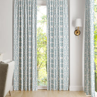 Chintz Mist Curtain Panels by Laura Park Designs in blue and white frame a window overlooking trees.