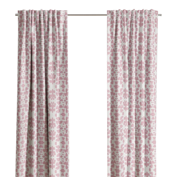 Chintz Rose Curtain Panels by Laura Park Designs, in pink and white, hang before a window with tree views.