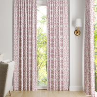 Chintz Rose Curtain Panels by Laura Park Designs, in pink and white, hang before a window with tree views.