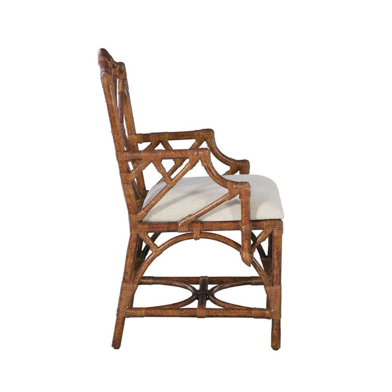 Side view of the Kenian Chippendale Arm Dining Chair in a tortoise finish, showcasing a wicker design with detailed armrests and a white seat cushion.