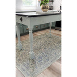 A Spicher and Company A Joy of Earth Vinyl Floor Mat lies under a light blue kitchen island with turned legs.