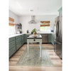 A modern kitchen with green cabinets, stainless appliances, a small island, and a Spicher & Company Joy of Earth vinyl mat.