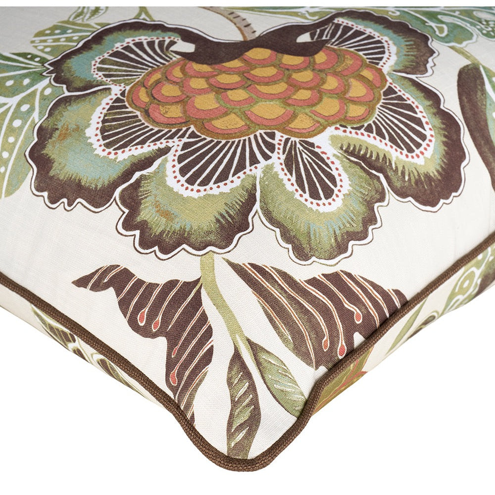 A close-up of a decorative throw pillow showing a large floral pattern in muted green, brown, ochre yellow, and terracotta on an off-white background.