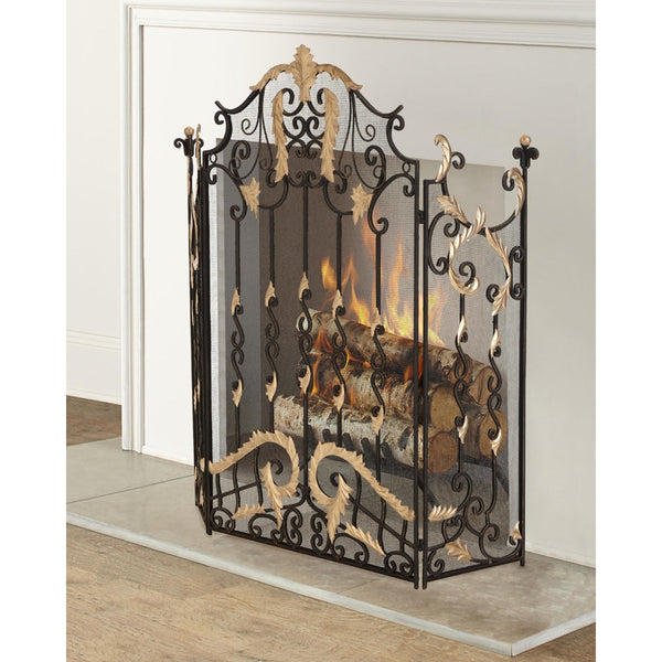 An ornate black wrought iron fireplace screen with gold-toned scrollwork accents, shown standing in front of a fireplace with logs and flames visible.