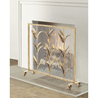 A gold-toned metal fireplace screen with leaf motifs and clear mesh panels, shown standing in front of a fireplace with a fire burning inside.