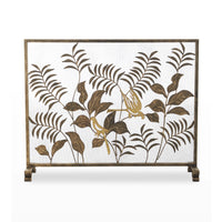 A decorative metal screen with a bronze-finished frame and legs, featuring cutout botanical leaves and two gold birds on a white mesh background.