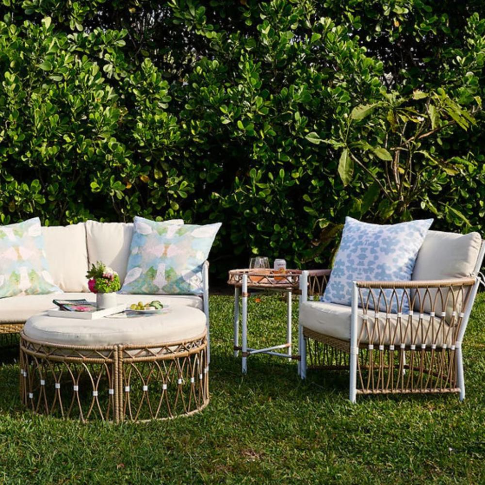 The Laura Park Designs Outdoor Chintz Mist Pillow is shown on grass with greenery in the background.