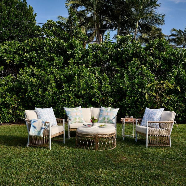 Four patio chairs and a round table with Laura Park Designs’ Outdoor Elephant Falls Pillows create a cozy outdoor space.