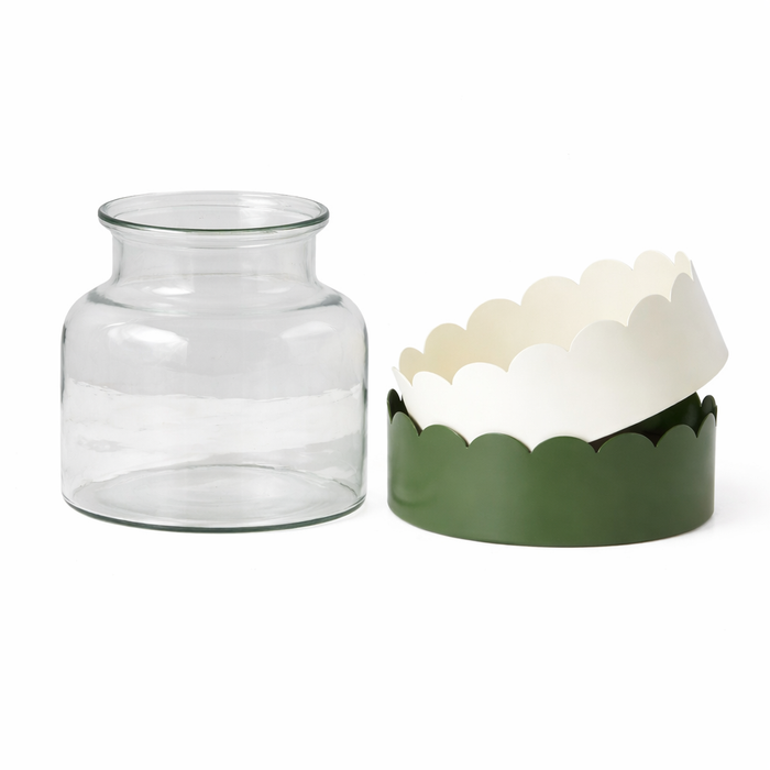 Clear glass jar next to a decorative container with scalloped edges and green base on a white background