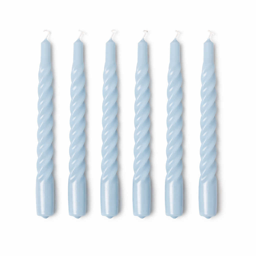 Set of six twisted light blue candles on a white background
