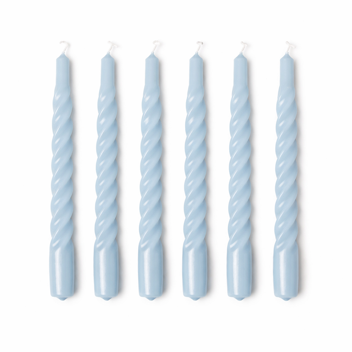 Set of six twisted light blue candles on a white background