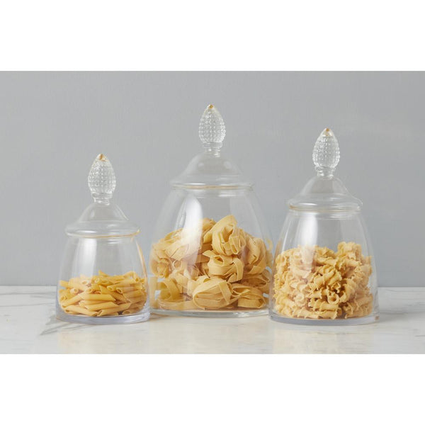 Three glass jars with lids containing different types of pasta on a gray background