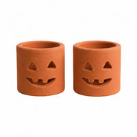 Two terracotta pumpkin-shaped candle holders with carved jack-o'-lantern faces, shown side by side on a plain white background.