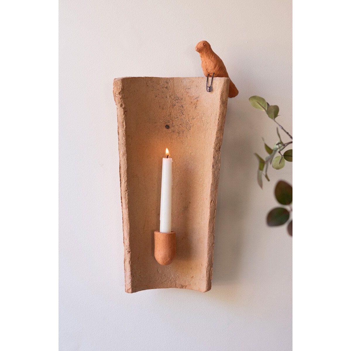 Clay wall sconce with a candle and bird on a white wall
