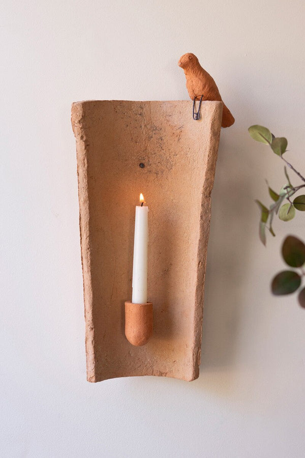 Clay wall sconce with a candle and bird on a white wall