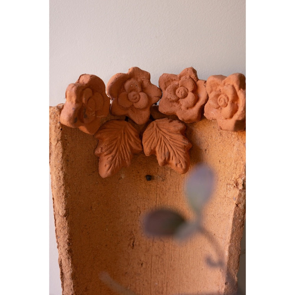 Terracotta wall sconce with floral designs on a plain background