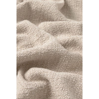 A close-up of a soft, textured beige fabric with a bouclé or chenille-like surface, shown in gentle folds and drapes.