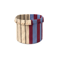 A cylindrical fabric storage basket with a striped pattern in beige, brown, blue, and burgundy, featuring fringed trim on the top edge, shown against a plain white background.