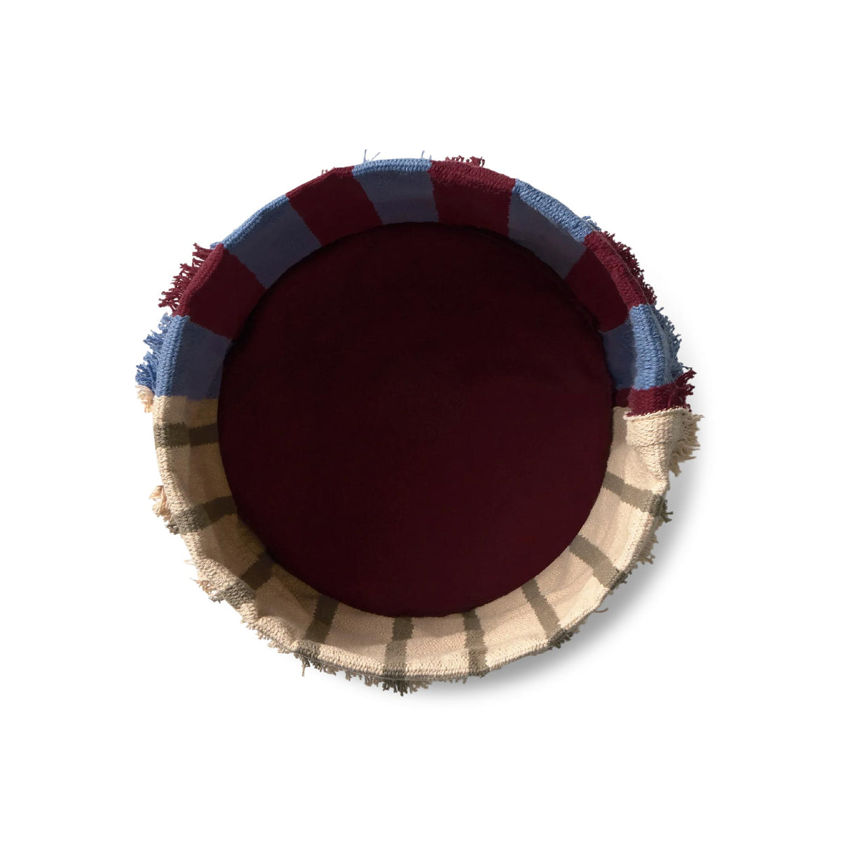 A round woven basket viewed from directly above, featuring a solid deep burgundy center, a blue and burgundy striped outer band, and a beige and brown plaid fringed edge, set against a plain white background.
